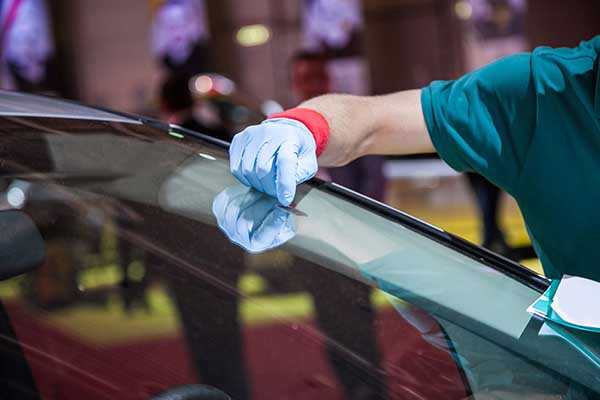 A windshield repair technician works to fill a rock chip.
